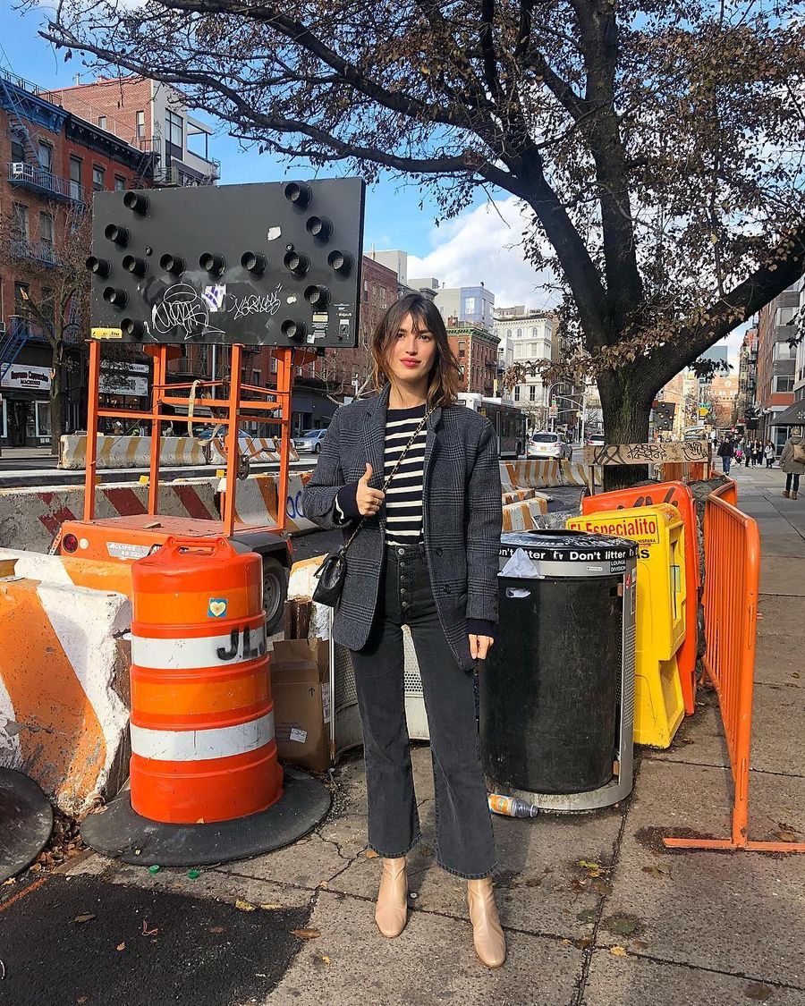 Jeanne Damas in NYC wearing a gray plaid blazer with striped shirt, black crop flare jeans and beige boots